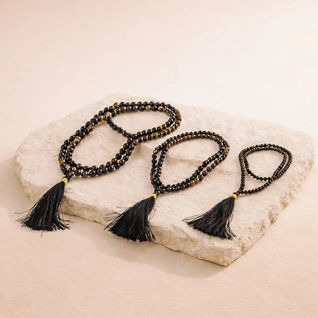 Black beaded necklace with tassels on a stone surface