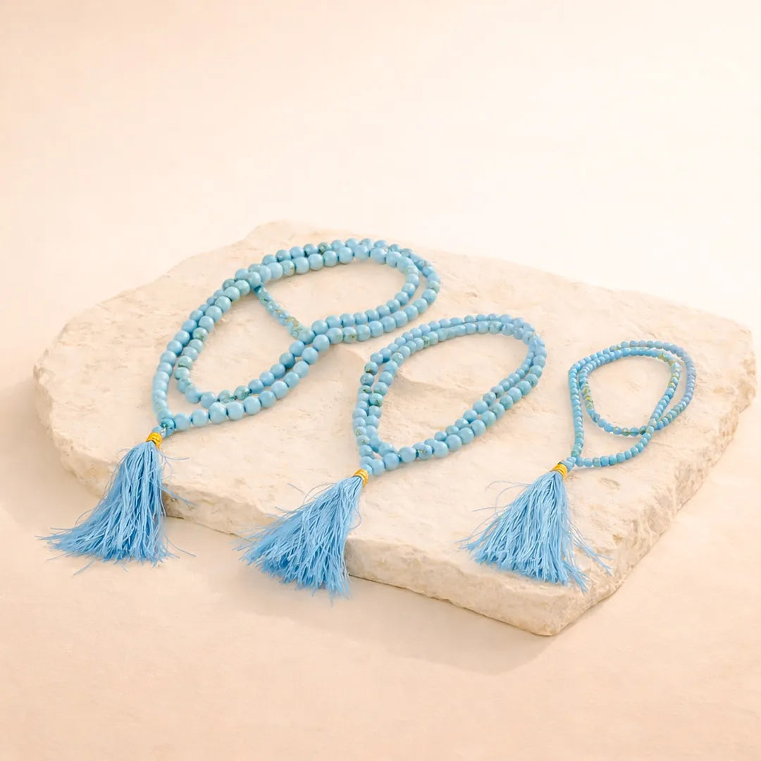 Blue beaded necklace with tassels on a stone surface