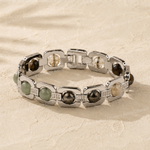 Silver bracelet with embedded stones on a beige fabric background