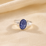 Silver ring with a blue stone on a beige fabric background