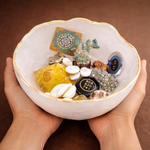 Person holding a white bowl filled with various decorative items against a brown background