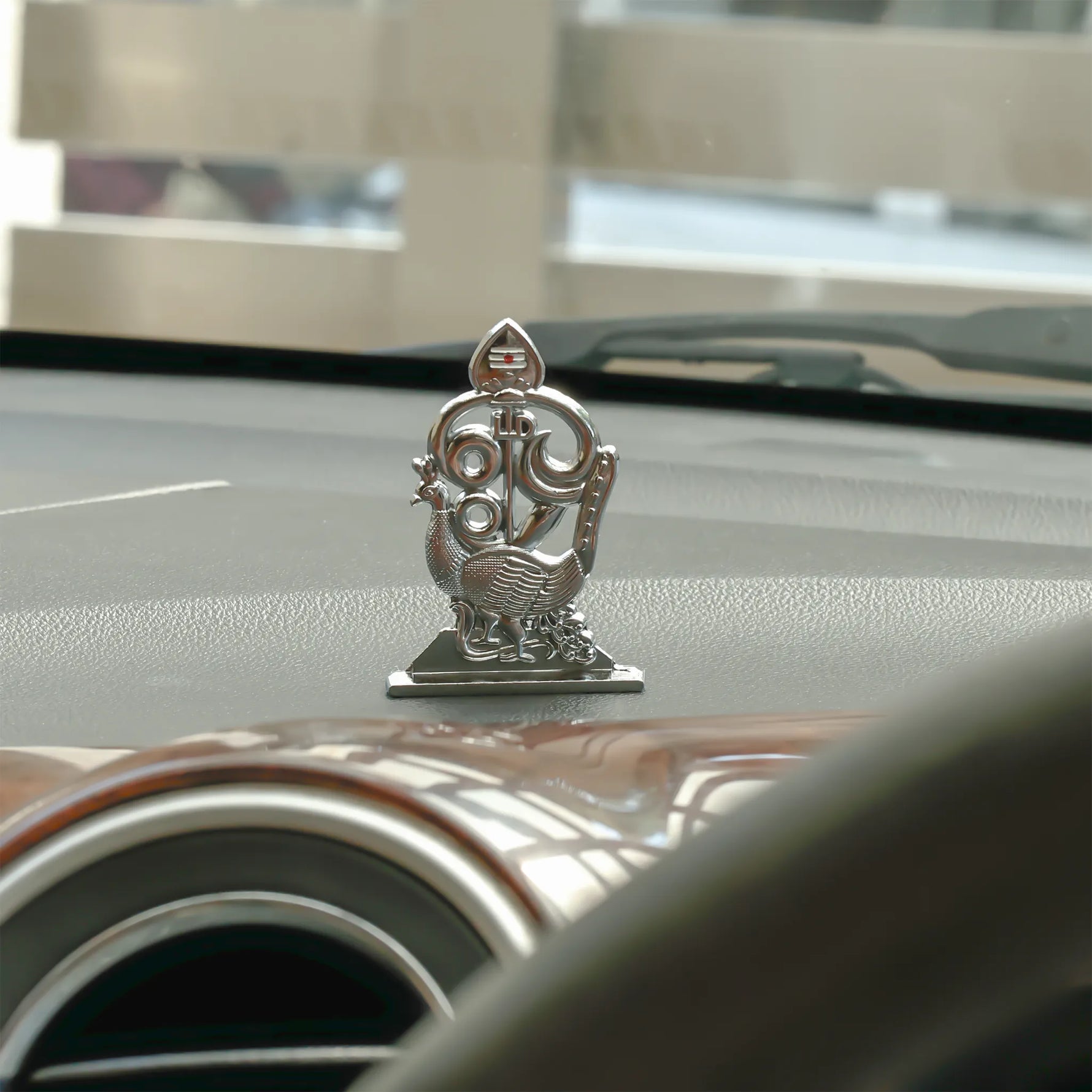 Decorative car emblem on a car hood with a blurred backgroundMurugan 1 Peacock Vel – Abhimantrit & Certified