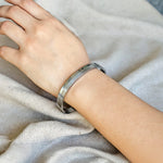 Silver bracelet on a person's wrist against a neutral background