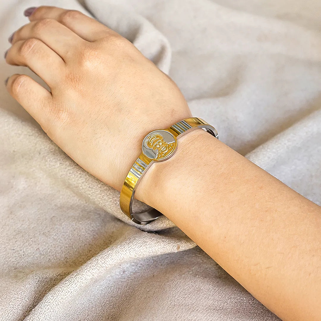 Gold and silver bracelet on a person's wrist against a neutral background