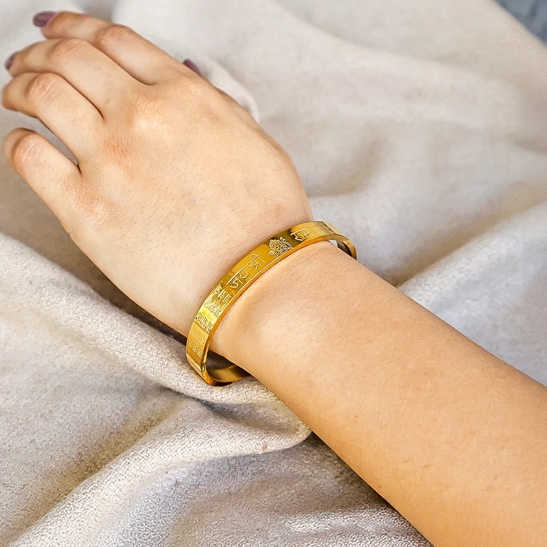Gold bracelet on a person's wrist against a neutral background