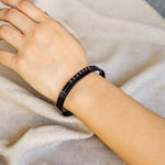 Black bracelet on a person's wrist with a neutral background