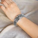Silver bracelet on a person's wrist against a neutral background