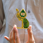 Decorative object with peacock design held by a person against a neutral background