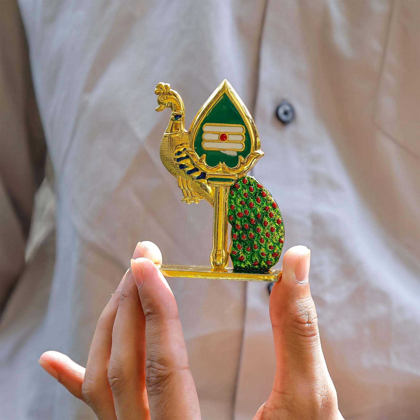 Decorative object with peacock design held by a person against a neutral backgroundPeacock Mina Vel – Divine Protection & Victory Pendant