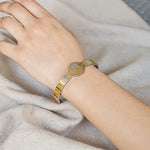 Gold bracelet on a person's wrist against a neutral background