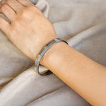 Silver bracelet on a person's wrist against a neutral background