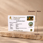 Precise Gemological Laboratory identification report card for a natural green jade stone on a wooden surface.