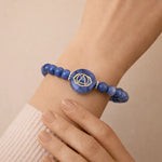 Blue beaded bracelet with a central circular design on a wrist against a beige background