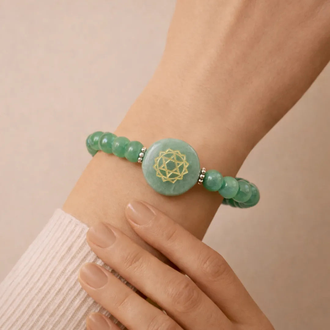 Green beaded bracelet with a central symbol on a wrist against a beige backgroundGreen Aventurine Heart Chakra Bracelet – Abhimantrit & Energized