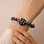Blue beaded bracelet with a central emblem on a wrist against a beige background