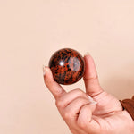 Hand holding a marbled stone ball against a beige background