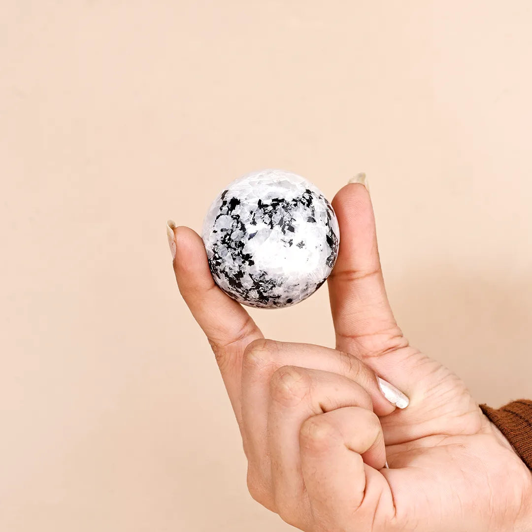Hand holding a snowball with a beige backgroundNatural Rainbow Moonstone Crystal Ball – Abhimantrit & Certified