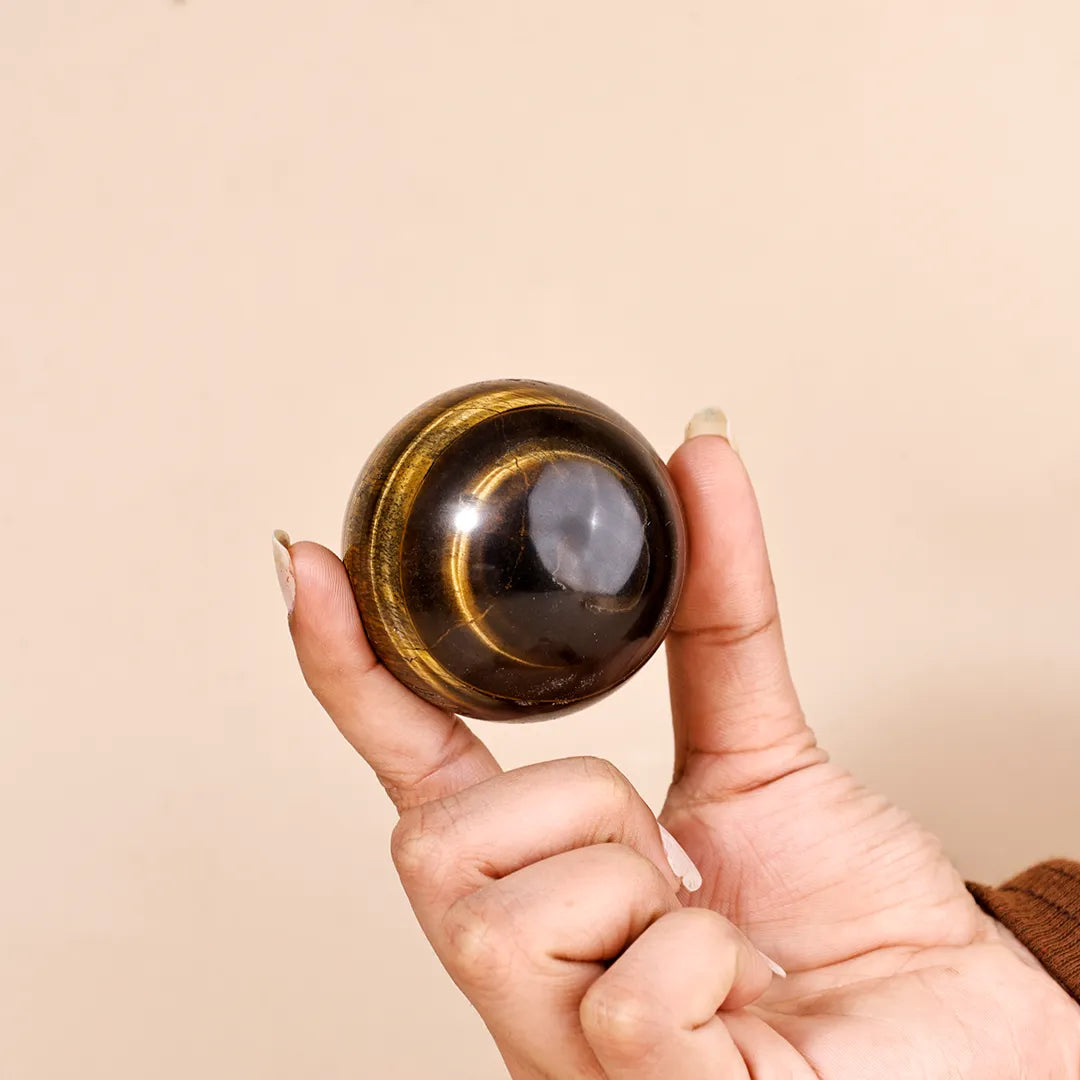 Hand holding a black crystal ball against a beige background