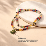 Colorful beaded bracelet with a green coin charm on a beige background, featuring text about ZIBU COIN and Goddess Lakshmi.