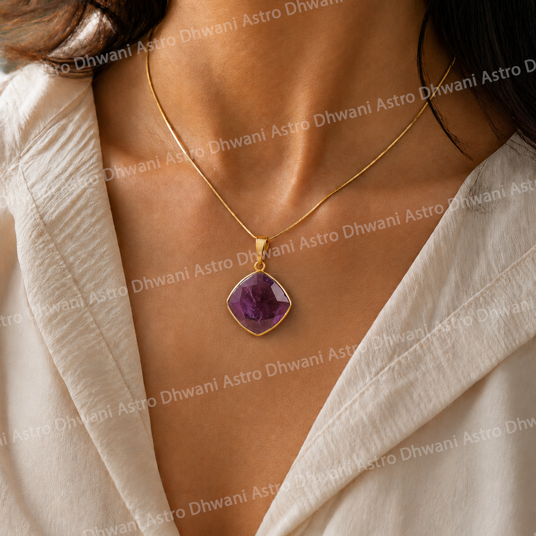 Gold necklace with a purple pendant on a person wearing a beige outfit.