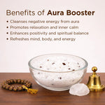 Bowl of salt, crystal, bell, and bracelet with 'Benefits of Aura Booster' text on a wooden surface.