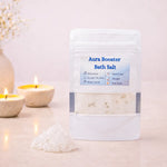 Aura Booster Bath Salt packaging with candles and a decorative vase on a light background