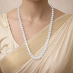 Pearl necklace worn by a person in a beige outfit