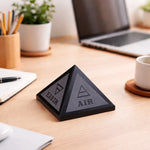 Pyramid-shaped decorative item on a desk with 'Earth' and 'Air' labels, surrounded by office supplies.