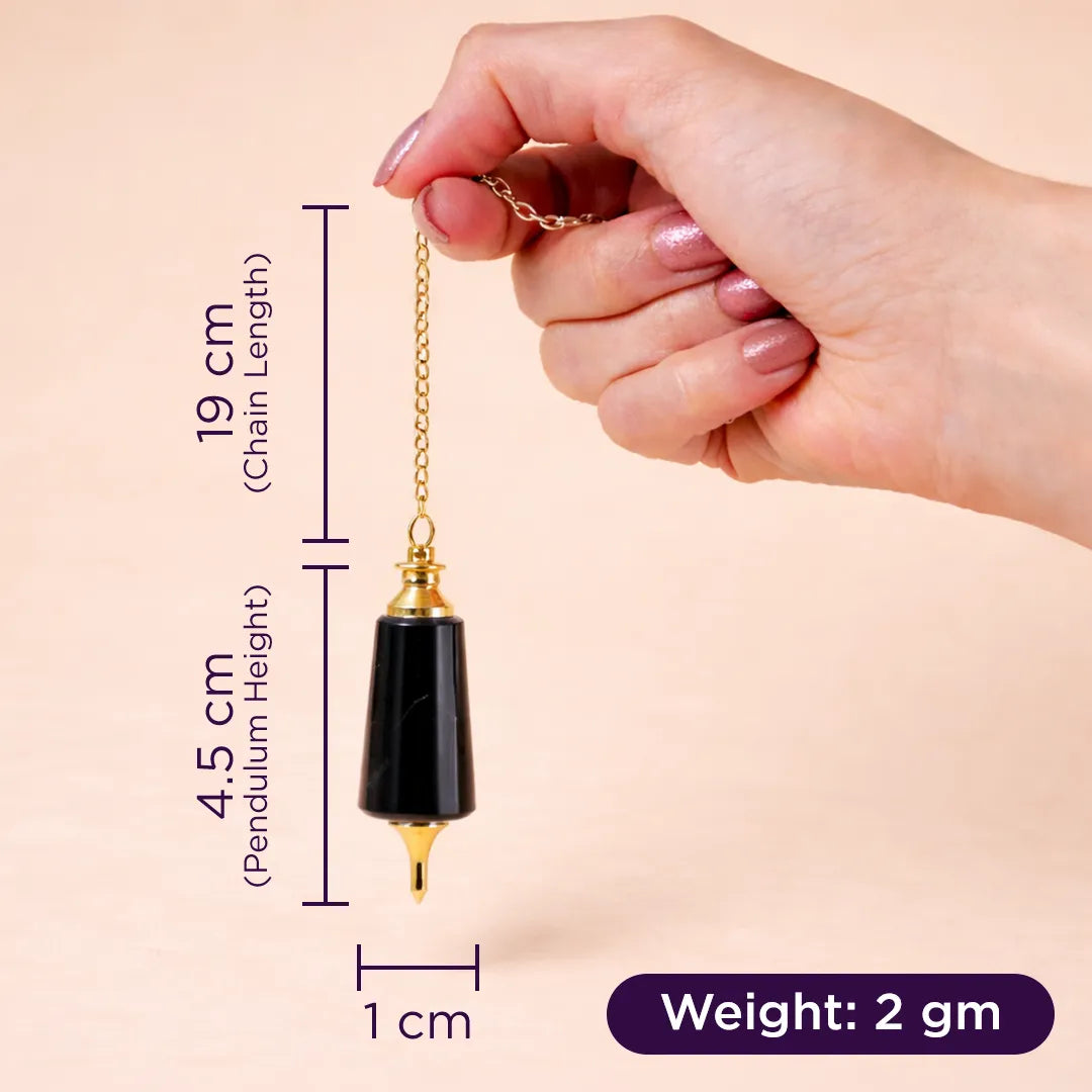 Hand holding a black and gold pendulum with measurements on a beige backgroundBlack Agate Pendulum for Protection, Grounding & Dowsing - Abhimantrit