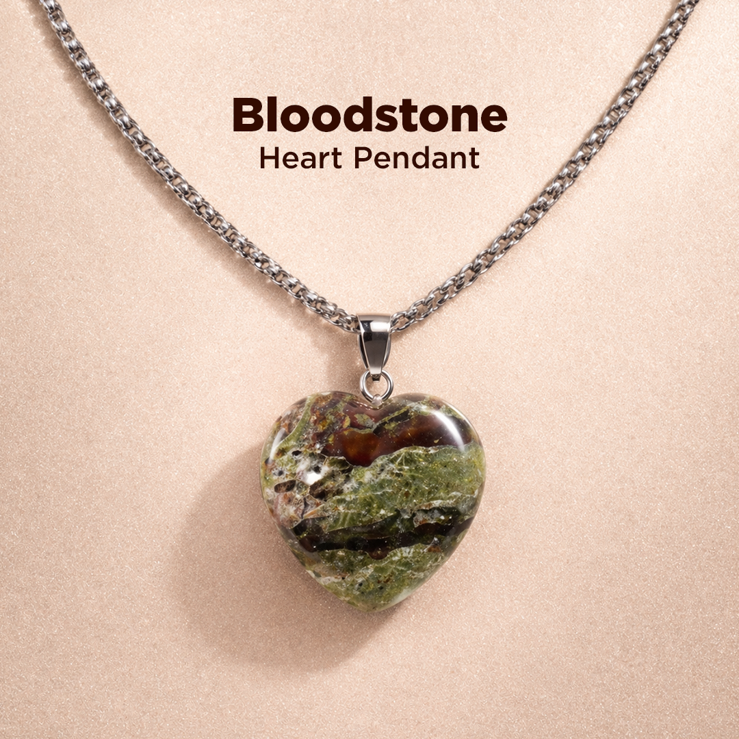Heart-shaped bloodstone pendant on a chain against a beige background
