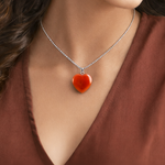 Heart-shaped pendant necklace on a person wearing a brown top