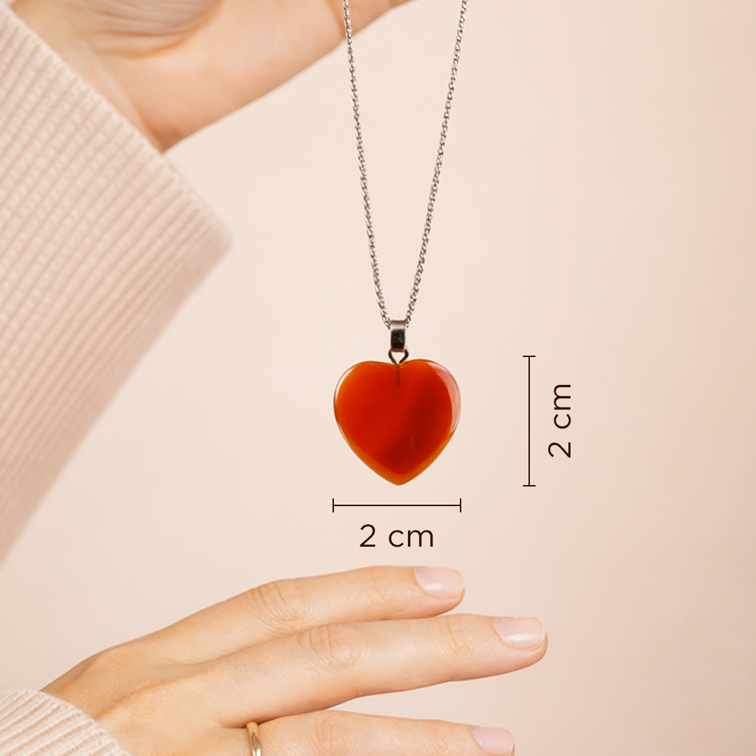 Red heart-shaped pendant necklace with measurements on a beige background