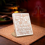 Decorative panel with intricate designs on a stand, placed on a textured surface with a blurred background.