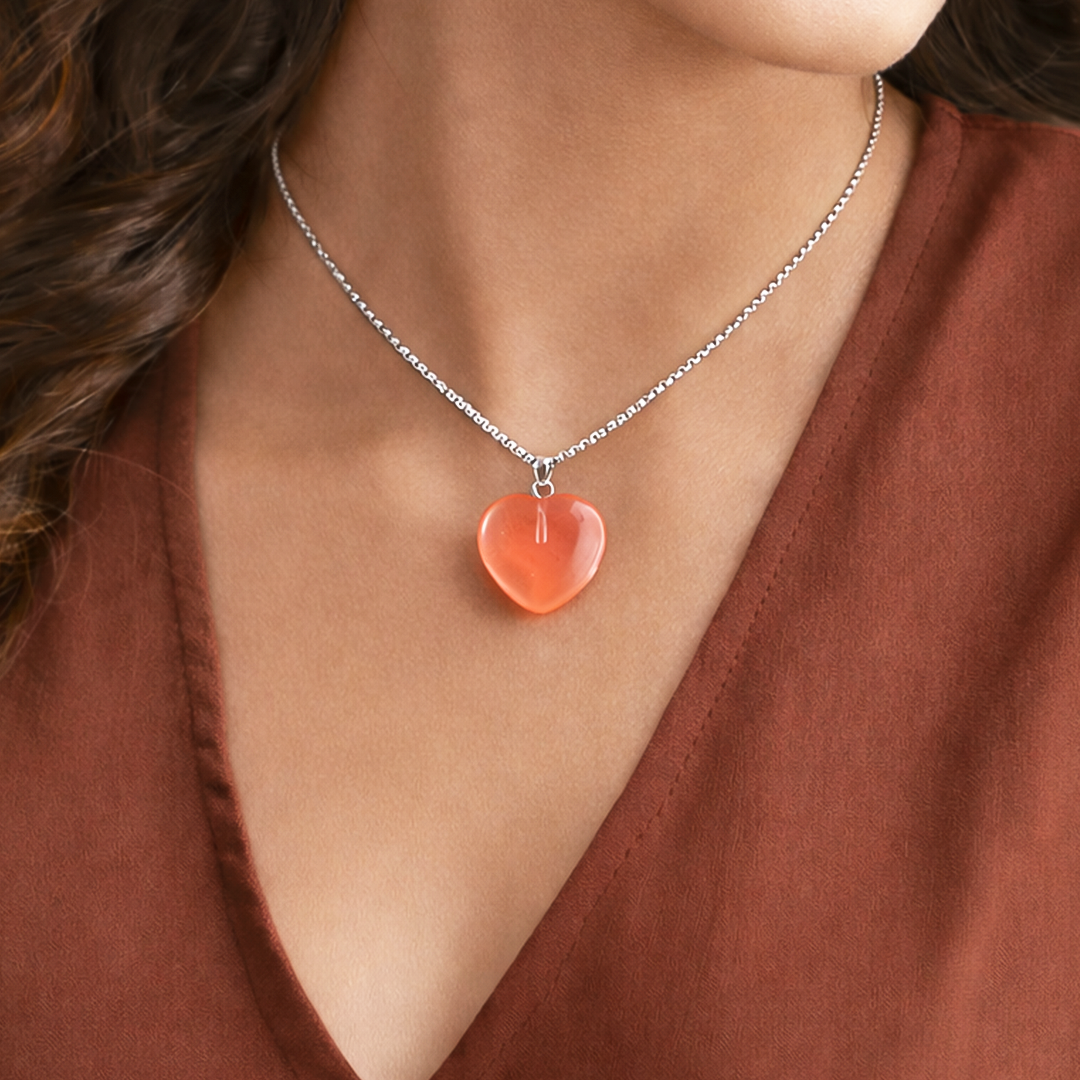 Necklace with a heart-shaped pendant worn by a person in a brown top