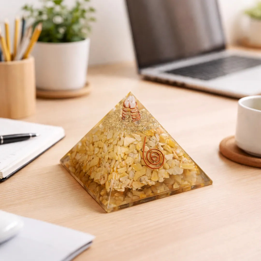 Pyramid-shaped object on a desk with laptop, notebook, and cup in the background