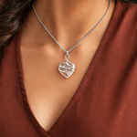 Silver heart-shaped pendant necklace on a person wearing a rust-colored top.