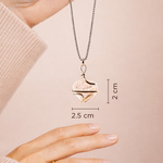 Heart-shaped pendant necklace being held by a hand with measurements displayed.