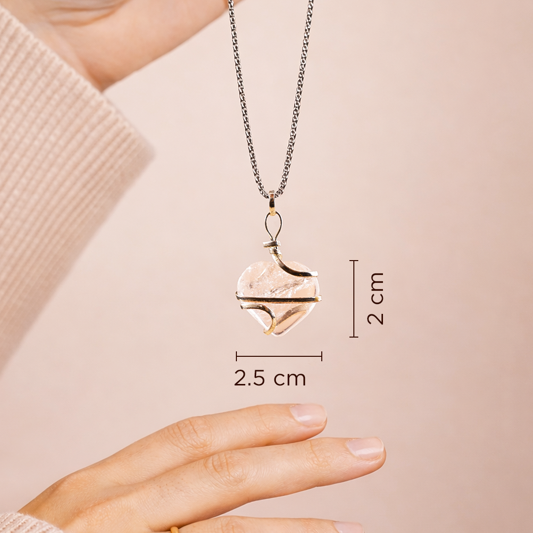 Heart-shaped pendant necklace being held by a hand with measurements displayed.Clear Quartz Wrap Heart Pendant (Abhimantrit) for Clarity & Energy