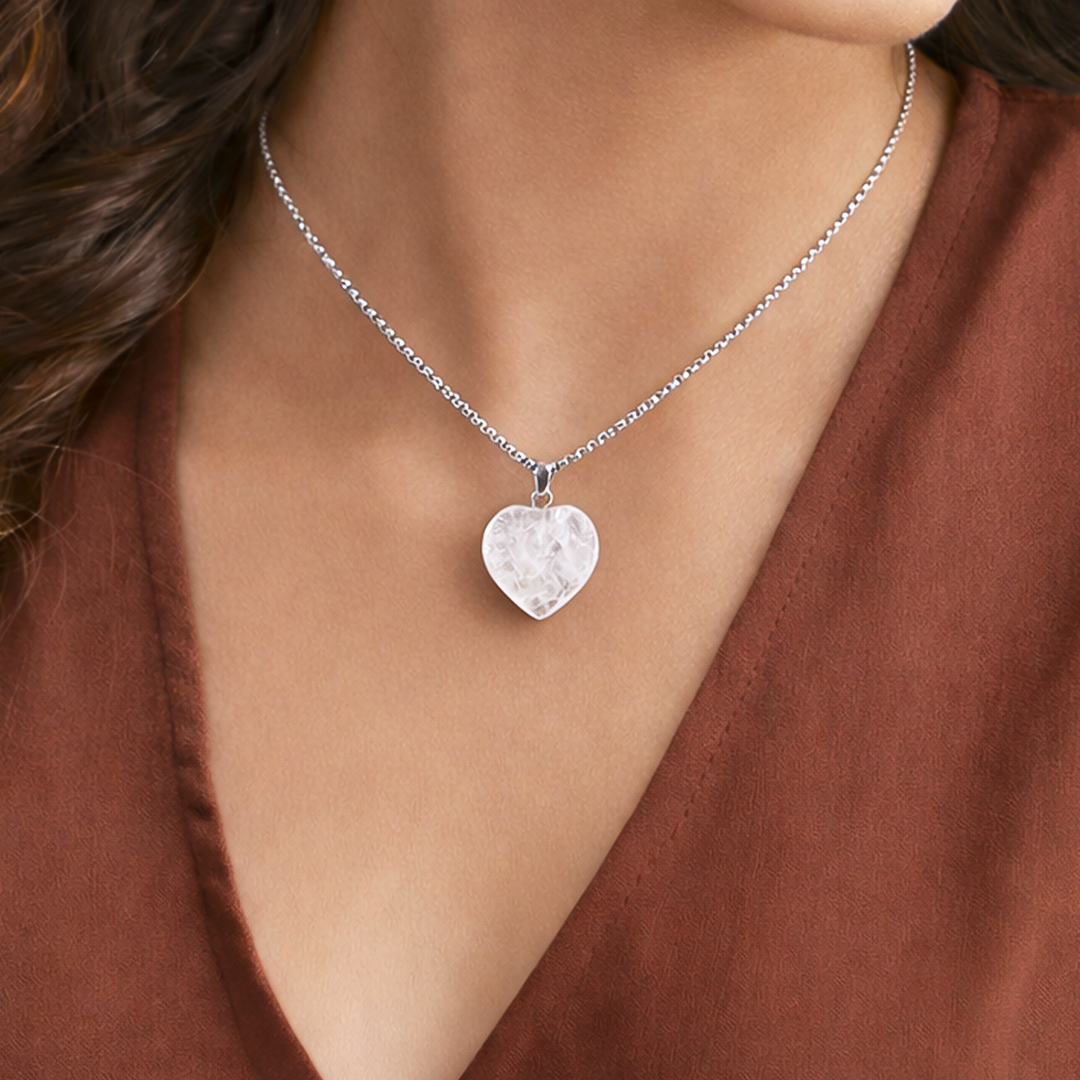 Heart-shaped silver pendant necklace on a person wearing a brown topClear Quartz Heart Pendant (Abhimantrit) for Clarity & Healing