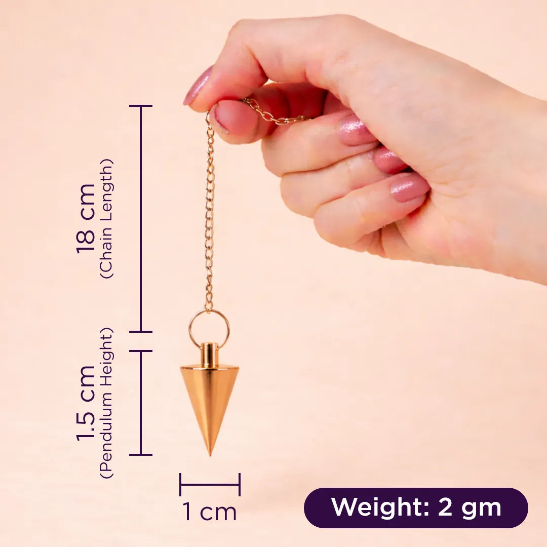 Hand holding a gold pendulum with measurements on a beige background