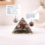 Pyramid-shaped crystal with pyrite stones and copper spiral on a white background