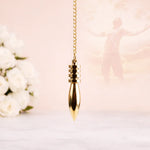 Gold pendant necklace on a soft pink background with white flowers