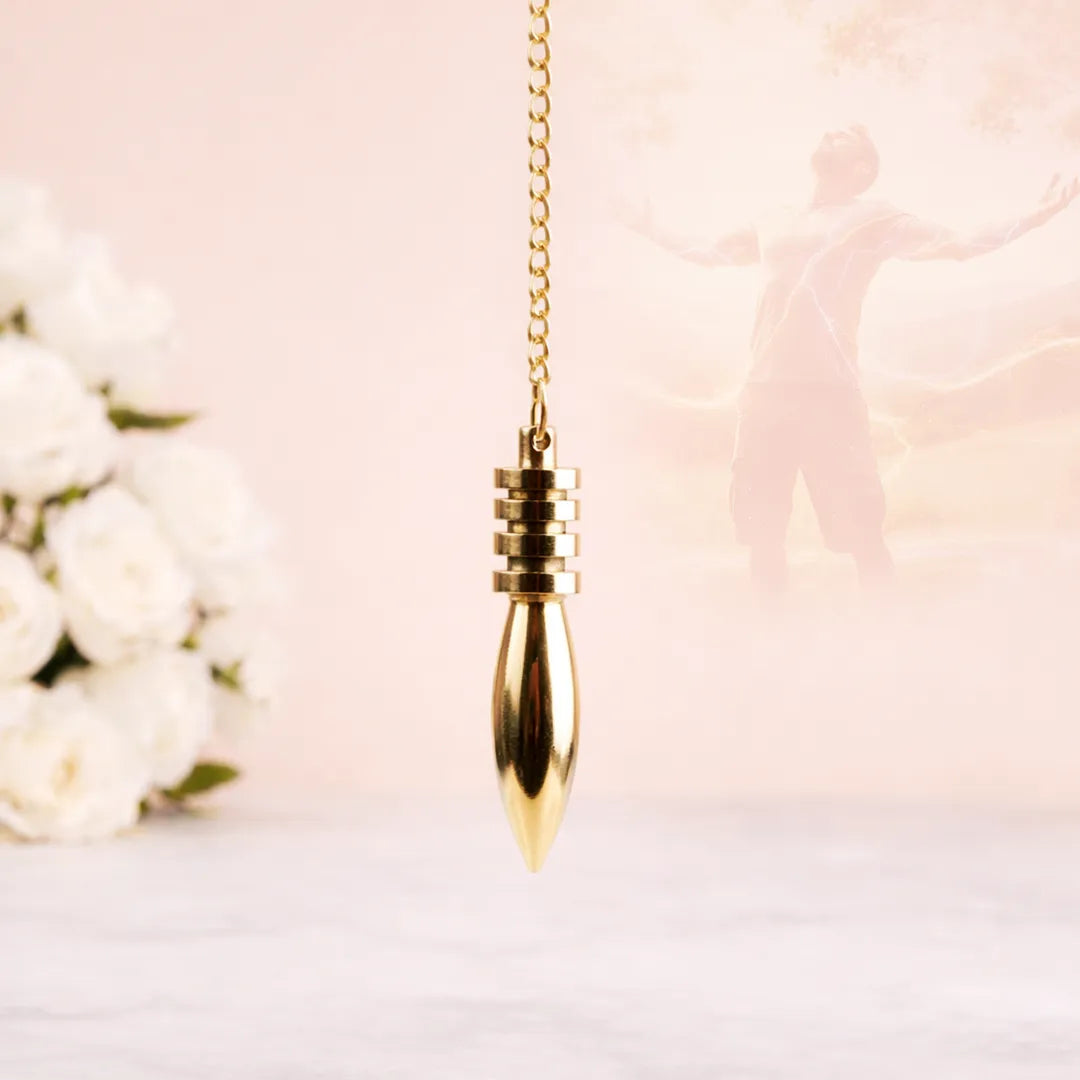 Gold pendant necklace on a soft pink background with white flowersEgyptian Brass Pendulum for Accurate Dowsing & Energy Healing - Abhimantrit