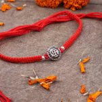 Elegant 925 Silver Swastik Rakhi displayed with diya, kumkum, and gift box for Raksha Bandhan celebrations.