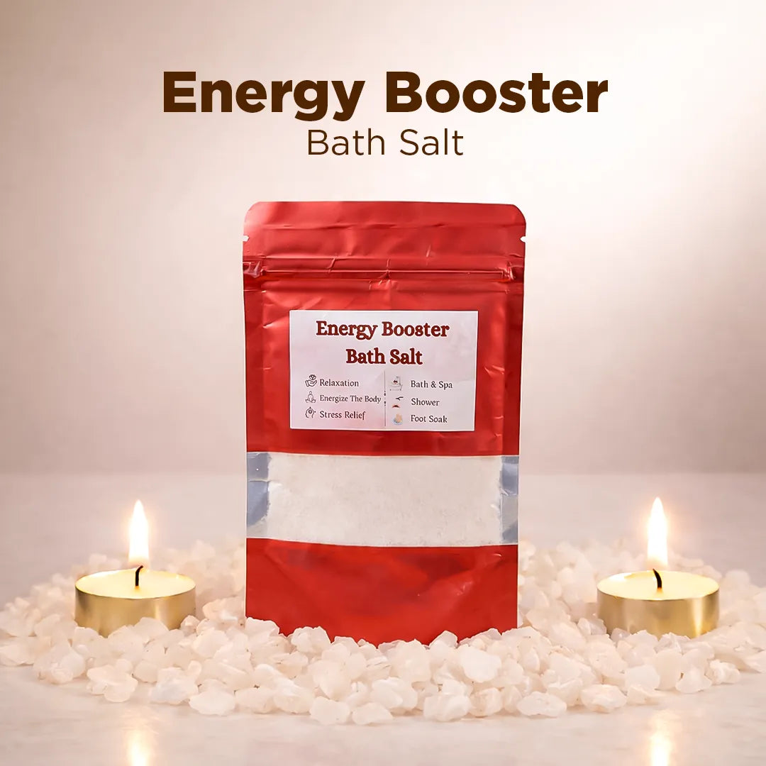 Red package of 'Energy Booster Bath Salt' with candles and pebbles on a light background