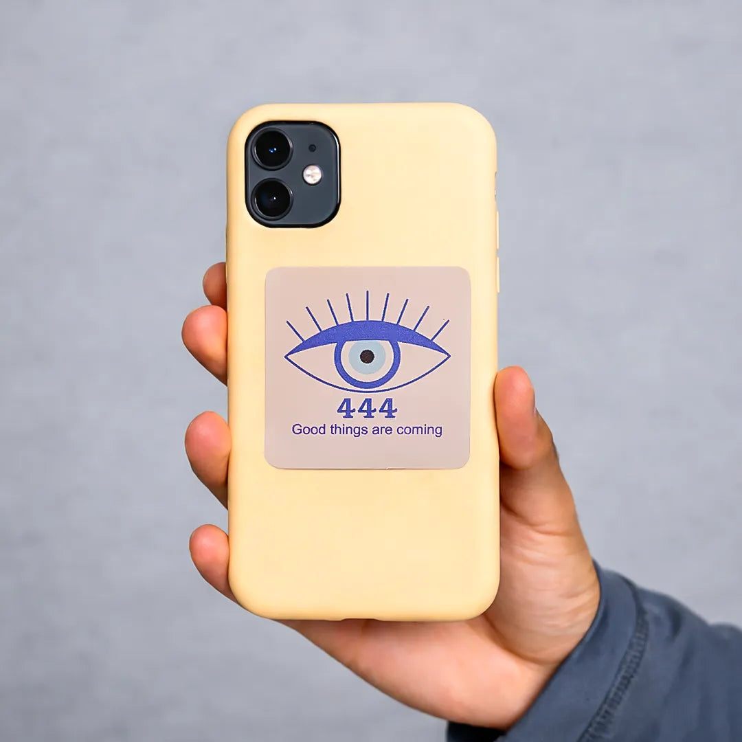 Hand holding a yellow phone case with an eye design and text on a gray background