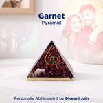Garnet pyramid with a spiral design on a white surface, with a blurred background of people.