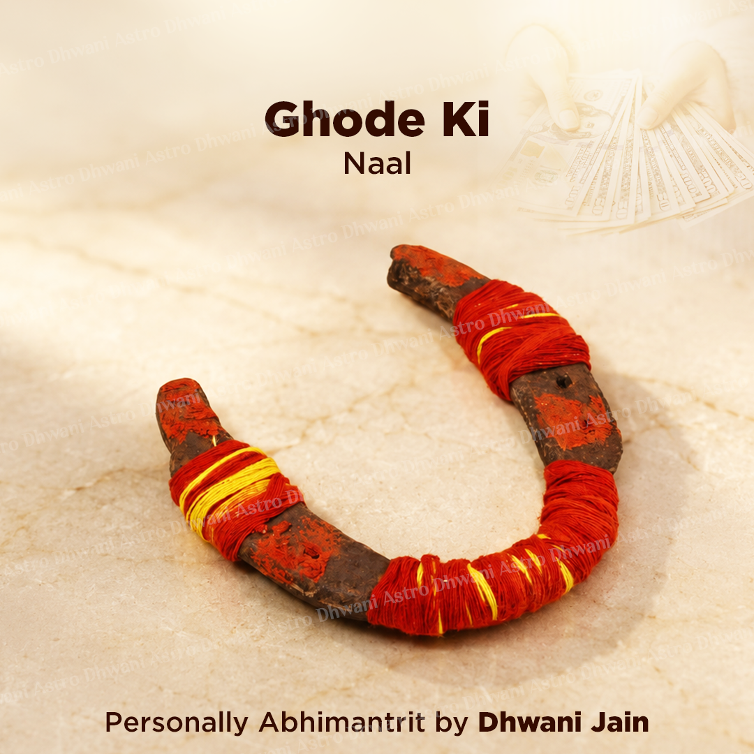 A curved U-shaped object wrapped with red and yellow thread, shown on a light beige marble-like surface with text reading 'Ghode Ki Naal' and 'Personally Abhimantrit by Dhwani Jain'.