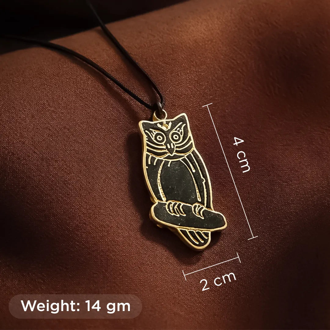 Gold owl pendant on a brown surface with measurements and weight information.
