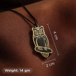 Gold owl pendant on a brown surface with measurements and weight information.